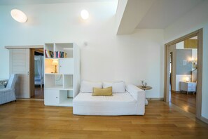 A modern living room with a white sofa, a bookshelf, and a small side table. - Crethion | Private Pool, Jacuzzi, Gym & Games Room (Violi Charaki)