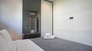 Ett hotellrum med en säng, en spegel, en dörr och en handduk på golvet.