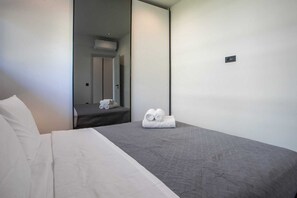 A hotel room with a bed, a mirror, a door, and a towel on the floor. - Kennedy 16 Urban Escape Rhodes Town, Apartment (Rhodes)