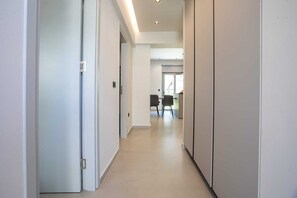 A corridor with doors on both sides, leading to a dining area with chairs and a table. - Kennedy 16 Urban Escape Rhodes Town, Apartment (Rhodes)