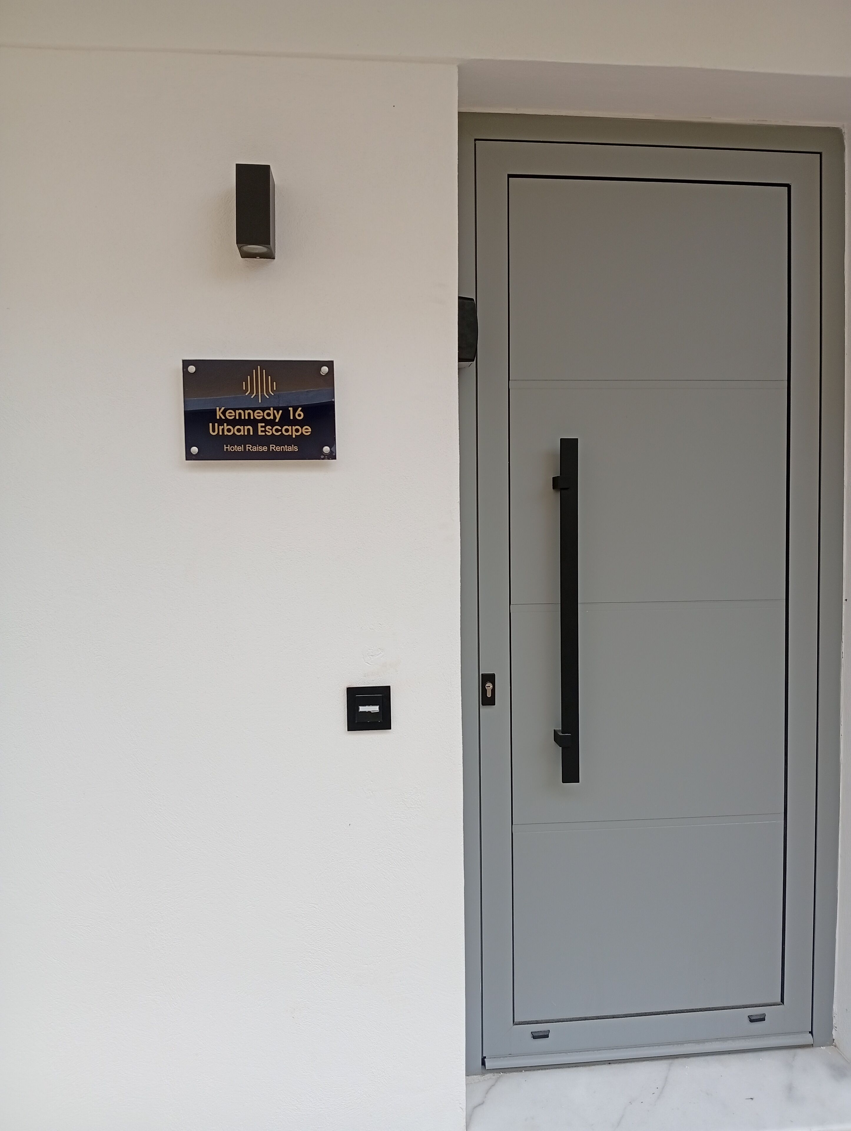 A door with a sign above it that reads 'Kennedy 16 Urban Escape Hotel Raise Rentals.'