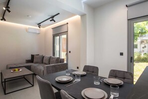 A modern dining area with a table set for four, a sofa, and a small coffee table. - Kennedy 16 Urban Escape Rhodes Town, Apartment (Rhodes)