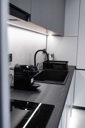 A modern kitchen with a built-in coffee machine, a sink, and a black coffee pot. - Kennedy 16 Urban Escape Rhodes Town, Apartment (Rhodes)