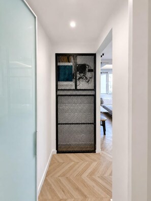 A hallway with a glass door, a black mesh partition, and a herringbone-patterned floor. - Mandilara City Hideaway – Adults Only (Rhodes)
