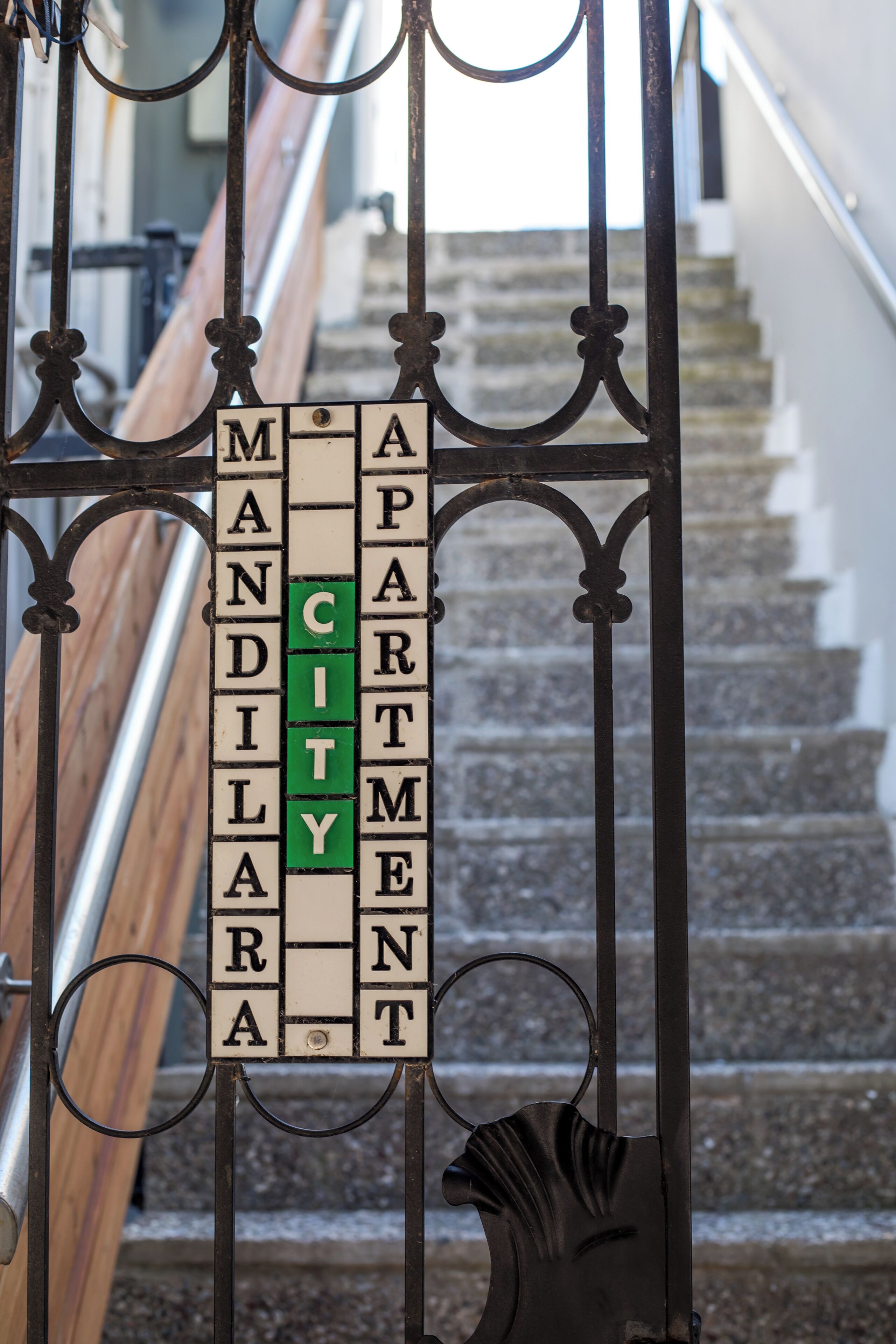 A staircase with a metal railing and a sign indicating 'CITY' apartments.