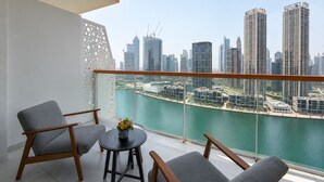 Un balcone con due poltrone grigie, un tavolino rotondo con un vaso e vista sulla città, con affaccio su un corpo d'acqua e palazzi alti.