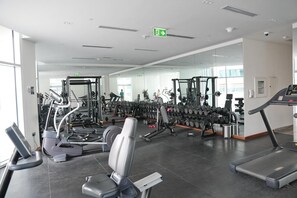 Ein Fitnessstudio mit verschiedenen Trainingsgeräten, darunter Laufbänder, Crosstrainer und Gewichtswertstationen.