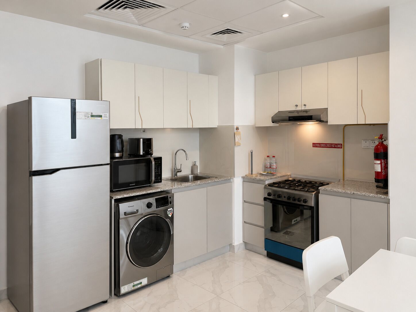A modern kitchen with stainless steel appliances, a washing machine, and a gas stove.