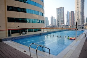 Una piscina con vista a la ciudad, rodeada de edificios modernos.