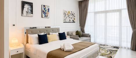 A modern bedroom with a large bed, a sofa, and artwork on the walls.