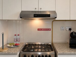 A kitchen with a stainless steel stove, a sign prohibiting electrical cookers, and a coffee machine. - Panoramic Burj Khalifa and Canal View, Business Bay, Dubai, UAE (Dubai)