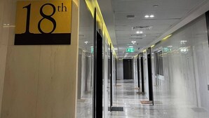 Un corridoio con un cartello che indica il diciottesimo piano, porte in vetro e un pavimento pulito e riflettente.