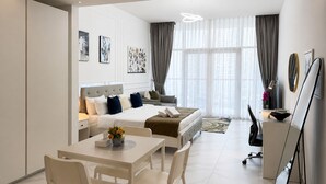 Una camera d'albergo moderna con un letto, una scrivania, una sedia e un'ampia finestra.