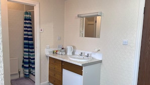 A bathroom with a white sink, wooden cabinet, and a mirror. - Coastal Place (Scarborough)