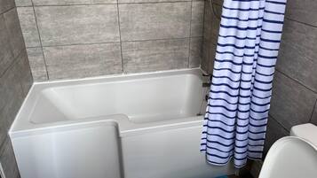 Un baño con bañera, cortina de ducha y retrete.