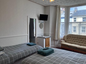 A hotel room with two beds, a TV, a small desk, and a sofa. - Coastal Place (Scarborough)