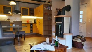 Un salon moderne comprenant un coin repas, une cheminée et une cuisine avec des meubles de couleur jaune.