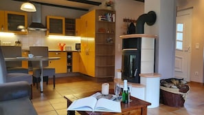 Ein modernes Wohnzimmer mit Essbereich, Kamin und einer Küche mit gelben Schränken.