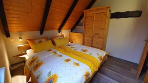 A bedroom with a bed, wooden wardrobe, and a nightstand with a lamp. - Romantic vacation home nestled in the heart of the Spreewald countryside—pure tranquility (Burg (Spreewald))