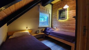 Une petite chambre accueillante, avec deux lits, une fenêtre donnant sur un beau paysage et un plafond en bois.
