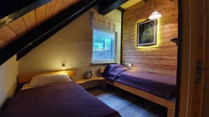 Ein kleines, gemütliches Zimmer mit zwei Betten, einem Fenster mit Ausblick und einer Holzbalkendecke.