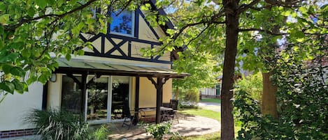 Ein traditionelles Gebäude mit überdachter Terrasse, Außenbestuhlung und Blick auf die umliegende Natur.
