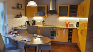 Une cuisine de taille réduite comprenant une table à manger, des chaises, une machine à café et une cuisinière.