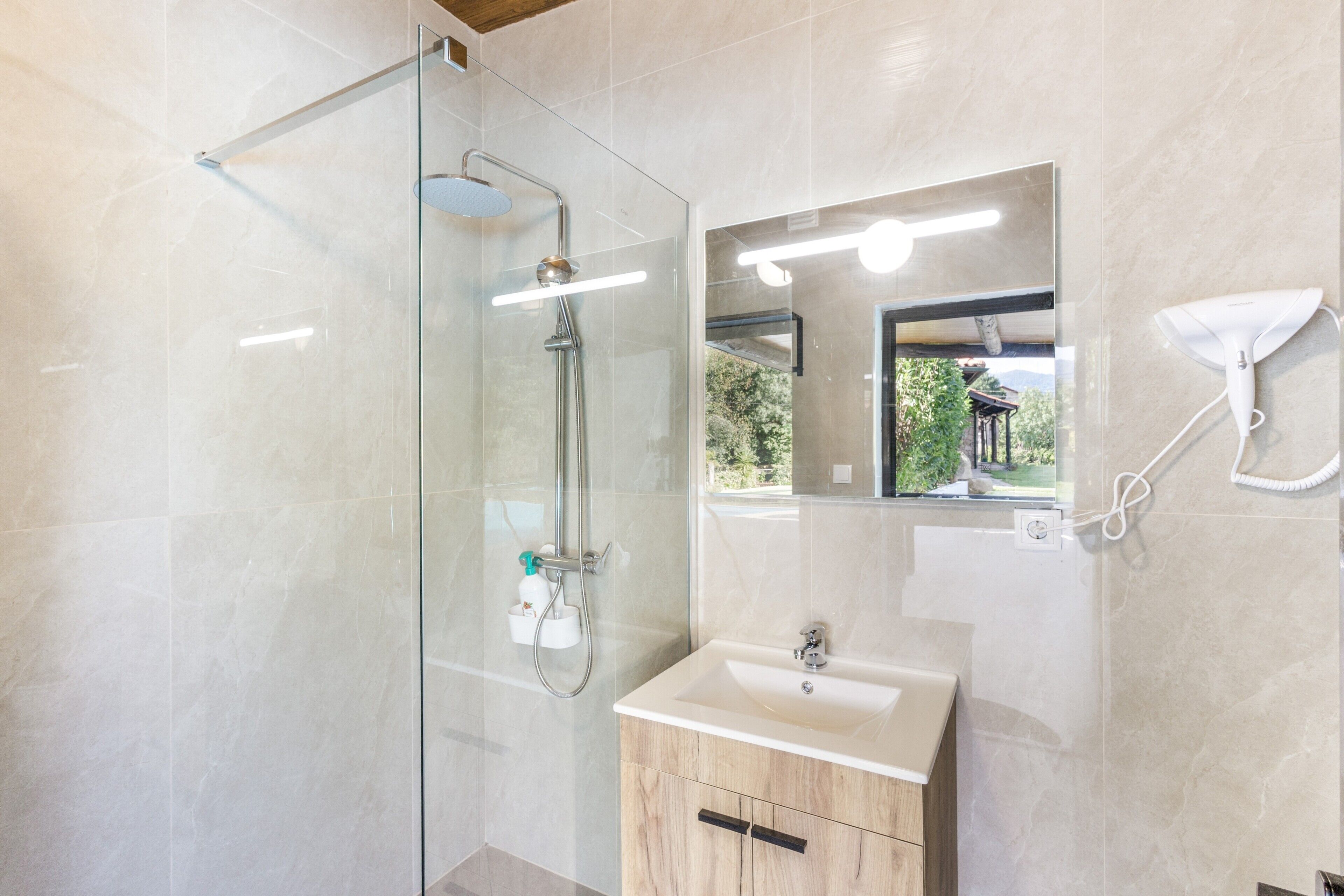 Une salle de bain moderne avec une douche à parois de verre, un meuble-lavabo et un miroir.