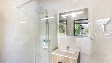 Une salle de bain moderne avec une douche à parois de verre, un meuble-lavabo et un miroir.