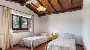 A room with two single beds, a window with curtains, a wooden ceiling, and a small table with a lamp. - Holiday Home 'Refúgio Da Nelinha' with Private Pool, Private Terrace and Wi-Fi (Rio Caldo)