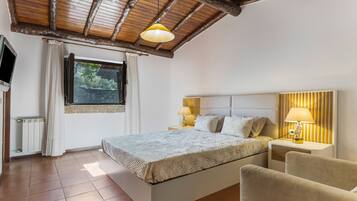 Un dormitorio con cama, dos mesitas de noche con lámparas, una ventana con cortinas y un televisor en la pared.