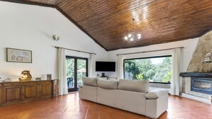 Un salón espacioso con techo alto, chimenea, ventana grande y televisor.