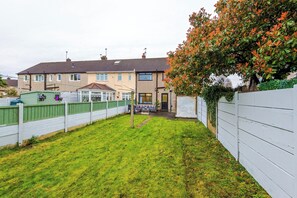 Ein Wohnhaus mit umzäunter Hinterhof, kleinem Garten und einem zweistöckigen Gebäude mit Ziegeldach.
