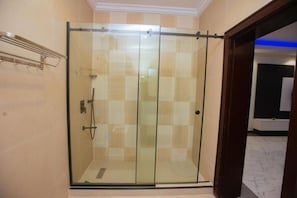 A glass-enclosed shower area with a metal handle and a towel rack on the wall.