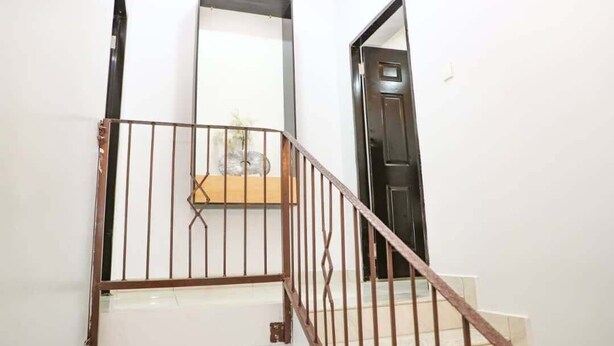 Una escala amb barana metàl·lica, un aplom metall i una porta a la part inferior.