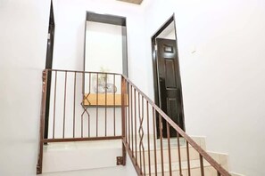 A staircase with a metal railing, a wooden handrail, and a door at the bottom. - Bamik Apartment (Abuja)