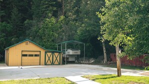 Eine gelbe Garage mit einem grünen Dach, einem überdachten Außenbereich und einem Baum im Vordergrund.