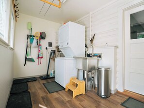 A laundry room with a washing machine, a sink, a trash can, and a small wooden stool. - Wolf Creek FishHouse (Wolf Creek)