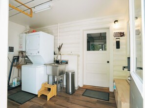 Un espace buanderie compact comprenant un lave-linge, un évier et une poubelle.