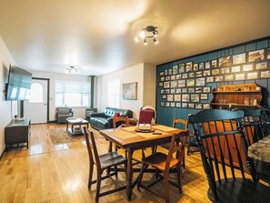 A living room with a wooden dining table, chairs, a sofa, and a wall adorned with framed pictures. - Wolf Creek FishHouse (Wolf Creek)