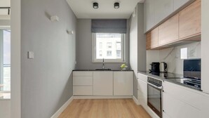 A modern kitchen with a window, built-in oven, and wooden cabinets.