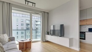 A modern living room with a sofa, TV, and a small round table.