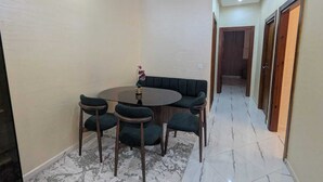 A dining area with a round table, four chairs, a sofa, and a vase with flowers.