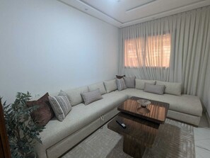 A living room with a sofa, a coffee table, and a remote control on a side table.