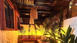 A tiled patio area with a bench, a hanging light fixture, and potted plants.