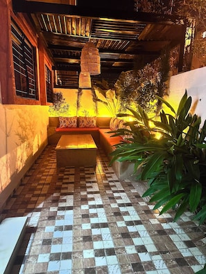 A tiled patio area with a bench, a hanging light fixture, and potted plants.