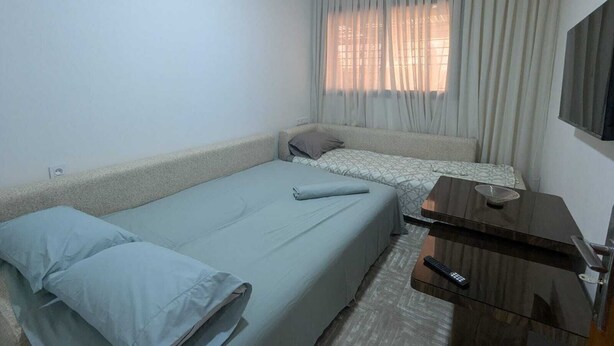A small, simple room with two beds, a flat-screen TV, and a desk.