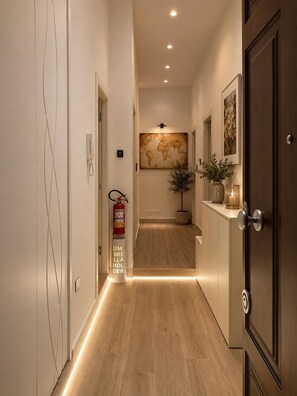 A hallway with a wooden floor, a fire extinguisher, a world map on the wall, and a door with a handle.