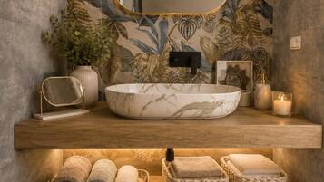 Un baño con un espejo grande, un lavamanos redondo y un mueble de tocador de madera.