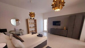 Ein modernes Schlafzimmer mit einem Bett, einem Nachttisch und einem an der Wand befestigten Fernseher.